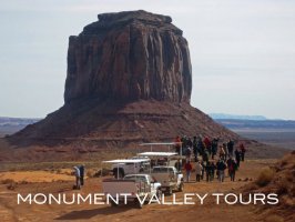 Tourists and vehicles at Monument Valley with large rock formation.
